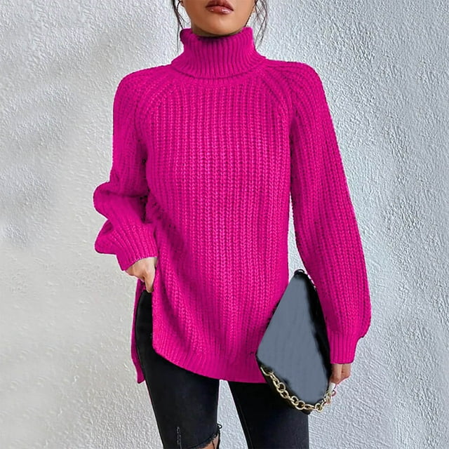 Woman wearing an oversized pink turtleneck knit sweater with long sleeves, textured waffle pattern, and side slits, styled with a black quilted handbag.