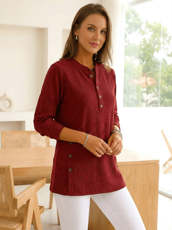 Woman wearing a red long-sleeve tunic top with side buttons.