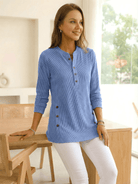 Woman wearing a light blue long-sleeve tunic top with side buttons.