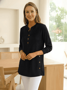 Woman wearing a black long-sleeve buttoned tunic top.