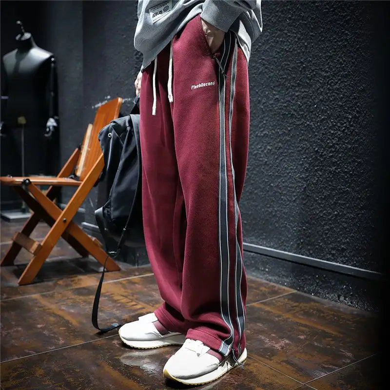 Man wearing loose maroon track pants with side stripes.