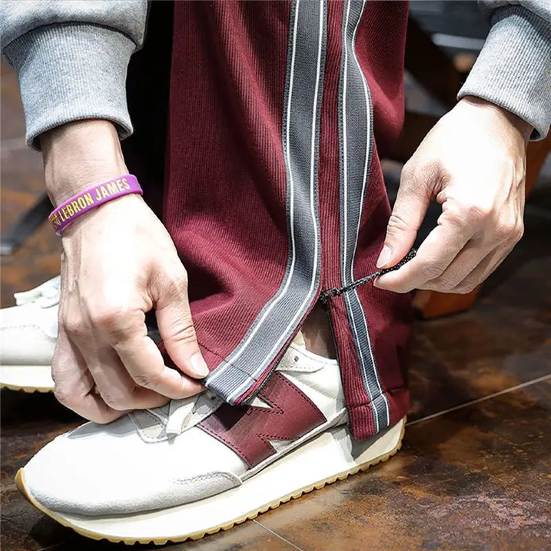 Close-up of maroon track pants with side zipper being opened.