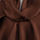 Close-up of chocolate brown fabric showing smooth, glossy texture and elegant draped folds.