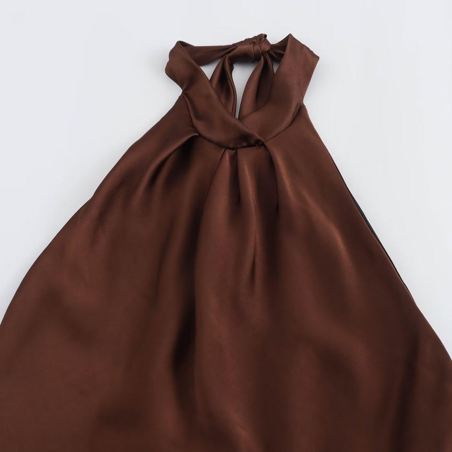 Detail shot of the pleated halter neck tie on a brown dress.