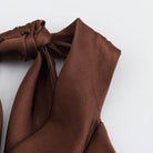 Side detail of the brown halter neck tie of dress.
