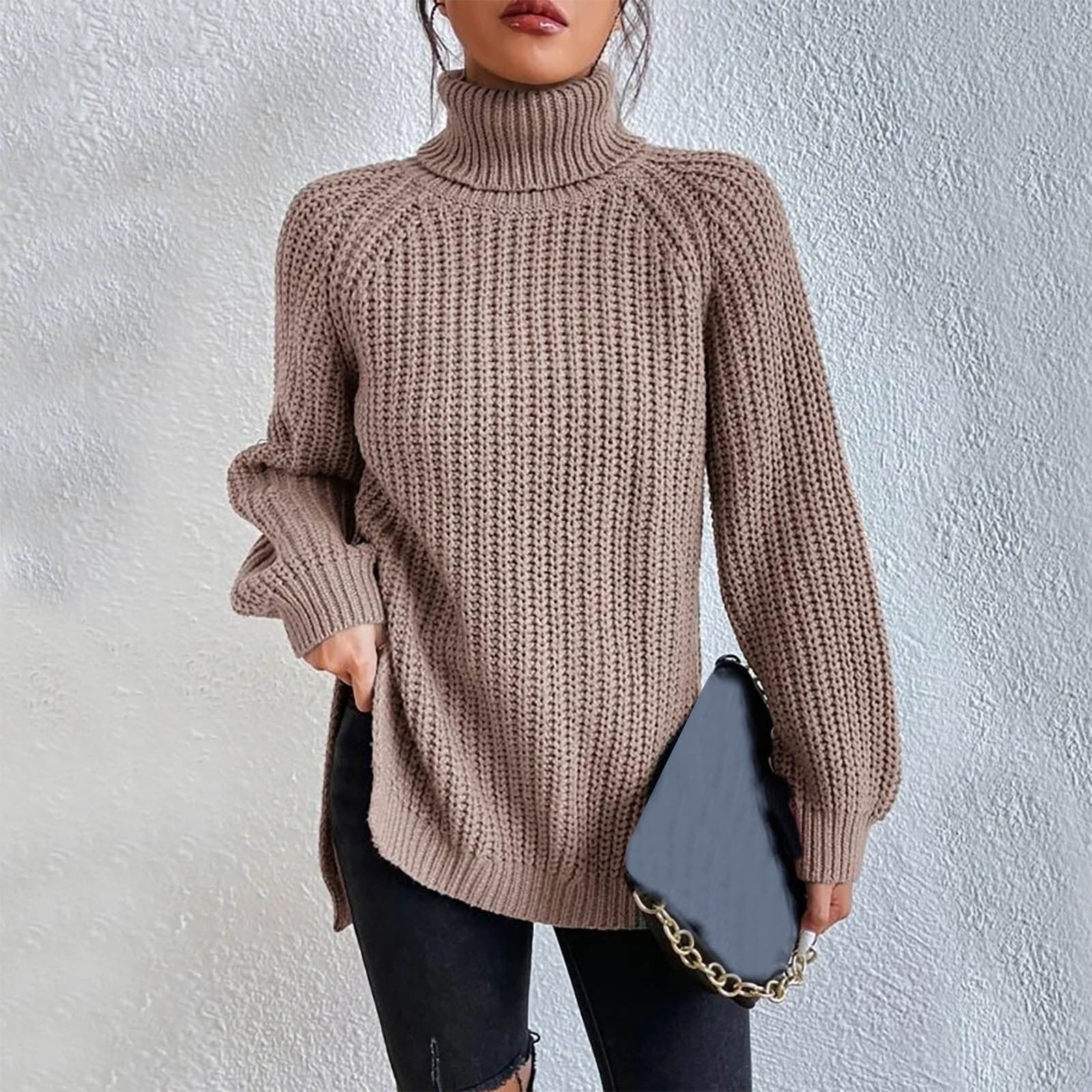 Woman wearing an oversized khaki turtleneck knit sweater with long sleeves, textured waffle pattern, and side slits, styled with a black quilted handbag.